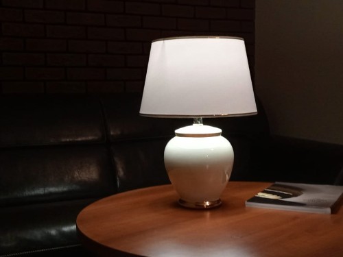 Ceramiczna lampka nocna z kolekcji ENVY z korpusem w kolorze kości słoniowej. Zdjęcie przedstawia zaświeconą lampkę.