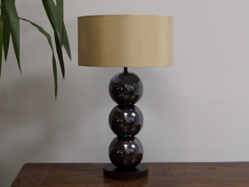 Lampa stołowa z kolekcji PERLA z trzema ceramicznymi kulami w kolorze opalizującego brązu i złotym cylindrycznym abażurem.