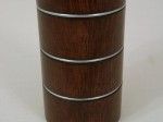 Zbliżenie pokazujące rysunek słojów świecznika wykonanego z drewna mango wraz z ozdobnymi metalowymi pierścieniami. 