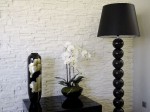 Czarna wysoka lampa podłogowa PERLA IX przeznaczona do salonu, apartamentu i każdego reprezentacyjnego wnętrza. Dziewięć ceramicznych kul na drewnianej podstawie w kształcie walca. Czarny perkalowy abażur w kształcie stożka.