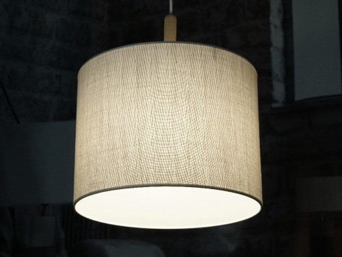 Dekoracyjna cylindryczna lampa sufitowa, w której zastosowano tkany materiał na abażur z najwyższej półki.