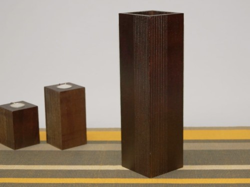 Nowoczesny wazon z drewna o przekroju kwadratowym w ciemno brązowym kolorze z dekoracyjnymi pionowymi wyżłobieniami.