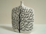 Biały, płaski wazon ceramiczny z dwustronnym motywem pozbawionego liści drzewa. Zabezpieczony od spodu filcowymi podkładkami.